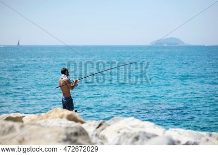 San Terenzo, Italy - May 2011: Man Fishing On A Rocky Beach Of San Terenzo Village. Gulf Of La Spezi