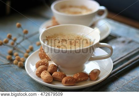 Two Cups Of Warm Sahlab On A Rustic Wooden Background.