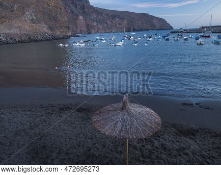 Sunset View Of Black Sand Beach Playa De Vueltas With Parasol, Fishing Boats And Ouk Cliffs. Valle G
