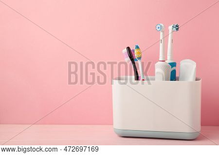 Holder With Modern Electric Toothbrushes And Manual Toothbrushes On Pink Background. Space For Text
