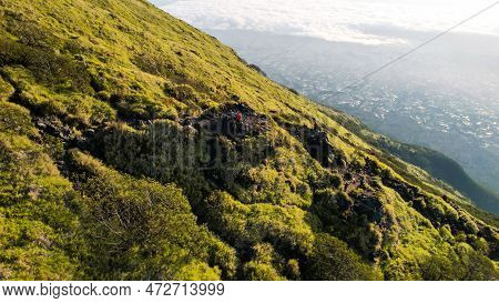 Asian Man Standing On Top Of A Nearby Mountain Looking At Mount Sindoro. West Java, Indonesia, March