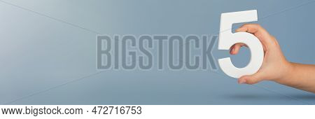 Number Five In Hand. Hand Holding White Number 5 On Blue Background With Copy Space. Concept With Nu