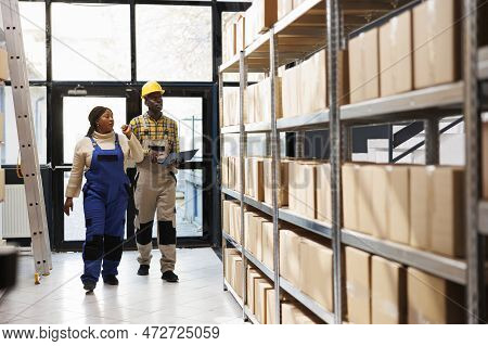 African American Warehouse Manager Teaching Trainee Supervising Stock Supply In Storage Room. Indust