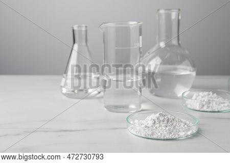 Petri Dishes With Calcium Carbonate Powder And Laboratory Glassware On White Marble Table. Space For