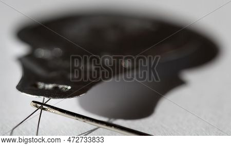 Sewing Needle Threader Tool In Use And A Single Black String.
