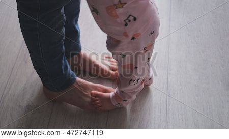 Cropped Image Of A Young Father And His Cute Little Daughter Dancing At Home. The Girl Stands On Her