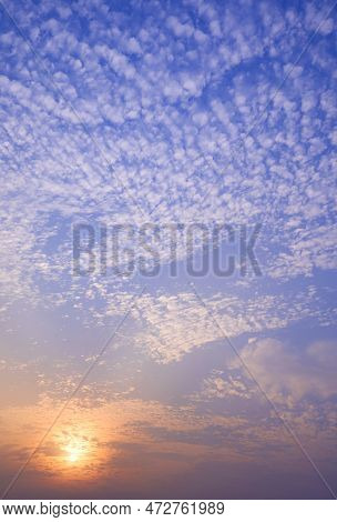 Dramatic Sunset Sky Background With Altocumulus Clouds And Orange Sunlight On Blue Dusk Sky In Verti
