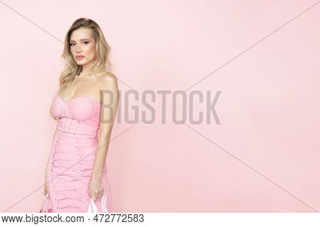 A Beautiful Attractive Woman With Blonde Hair In A Stunning Pink Dress On A Pink Background. Fashion