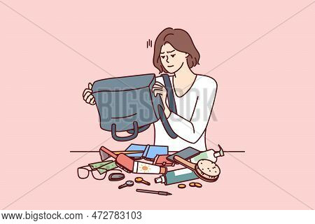 Puzzled Woman Shakes Out Contents Of Bag On Table Trying To Find Wallet With Money Or Mobile Phone. 