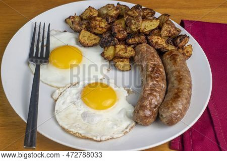 Two Fried Eggs Served With Home Fries  And Italian Sausages