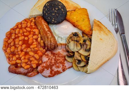 White Board With Full English Breakfast With Bacon, Fried Egg, Beans, Tomato, Roasted Sausage, Black