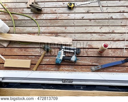 Interior Home Construction Of Wood Floor Being Installed Up To Exterior Door Jam With Carpenter Tool