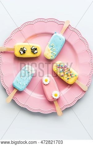 Top Down View Of A Pink Platter Of Colourful Cakesicles Decorated For Spring.