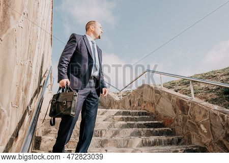 Confident Middle Age Businessman With Briefcase Walking Upstairs. Close-up Of Businessman Wearing Bl