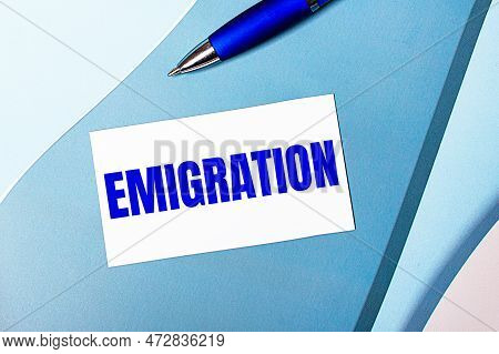 White Blank Card With Emigration Text And Blue Pen On Blue, Cyan And Pink Background.
