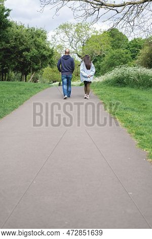 Vertical Photo Of A Multicultural Couple Walking On A Footpath In Figgate Park In Edinburgh In Sprin