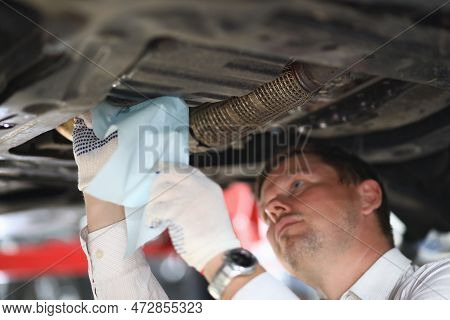 Auto Mechanic Inspects Car Leak And Suspension Parts Of Raised Car With Napkin At Repair Station. Se
