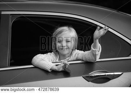 Cute Little Girl Traveling In The Car And Observing Nature From Open Window. Little Girl Waving Hand