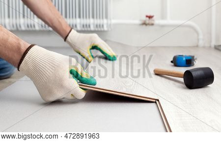 Man In Protective Gloves Lays A Laminate On The Floor. Repair And Decoration Of Premises. Modern Flo