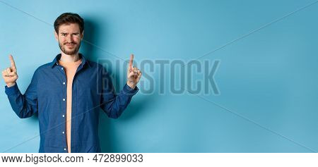 Skeptical Young Man Frowning And Squinting, Cringe From Something Disgusting, Standing On Blue Backg