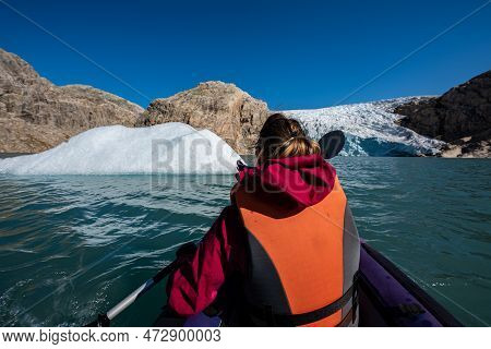 Young Woman Kayaking Mosevatnet Lake With Folgefonna Glacier In The Background, Visiting Norway