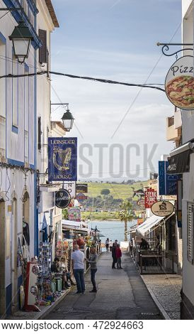 Alvor, Portugal, March 2023 - A Narrow Street With Bars And Souvernir Shops In The Town Of Alvor, Al