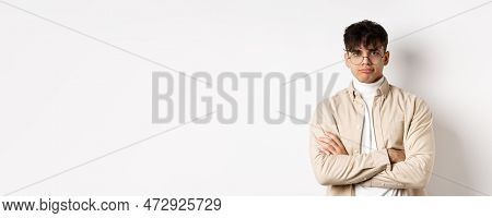 Image Of Stylish Hipster Guy In Glasses Feeling Bored, Looking Unamused With Pokerface, Cross Arms O
