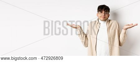 Portrait Of Handsome Young Man Looking Confused, Know Nothing, Shrugging Shoulders And Spread Hands 