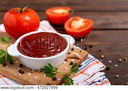 Cutting Board Witch Bowl Of Ketchup Or Tomato Sauce, Spices And Fresh Tomatoes On Wooden Table With 