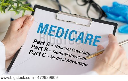 Medicare Part C Part A Part B In Hands Doctor In A White Coat And Sterile Gloves Holding. Medical Co