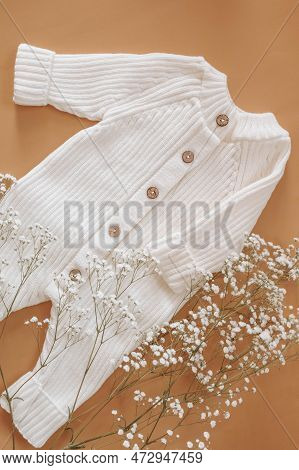 Jumpsuits For Newborns On A Beige Background Wihf White Flowers. Spring Clothes For Children