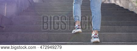 Close-up Of Woman In Jeans Going Up Steep Stairs. Female Tourist In Casual Clothes Going Upstairs Ou