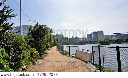 Walking Lane Of Iblur Lake With Green Cover And Clear Cloudy Skyn And Cityscape Infrastructure.