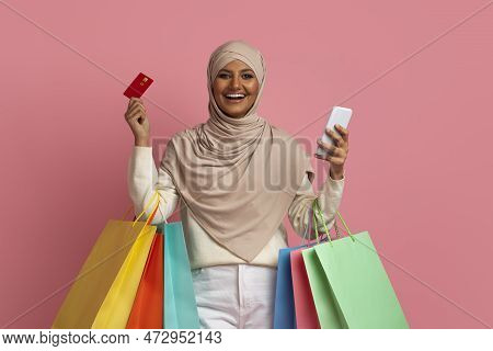 Happy Muslim Woman In Hijab Holding Smartphone, Creadit Card And Shopping Bags