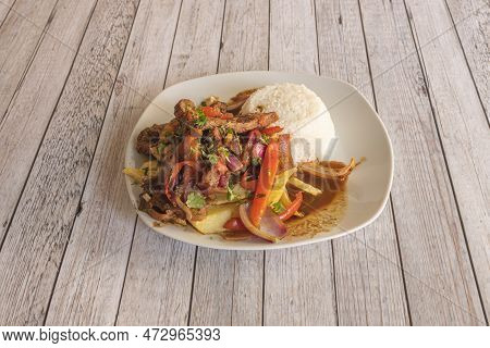 Plate Full Of Typical Peruvian Lomo Saltado Recipe Accompanied By Rice, Peppers And Red Onion And Ho
