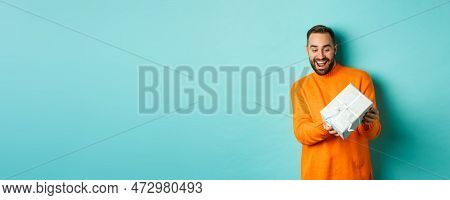 Holidays And Celebration Concept. Excited Man Receiving Gift, Looking Happy At Present And Smiling, 