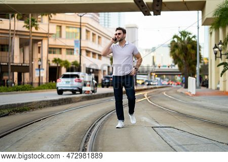 Young Handsome Man In Classik Polo T-shirt Chatting On Phone On The Street. Handsome Confident Styli