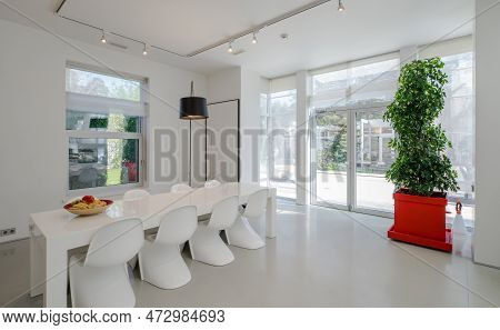 Modern Interior Of Spacious Living Room. White Dinner Table And Chairs.