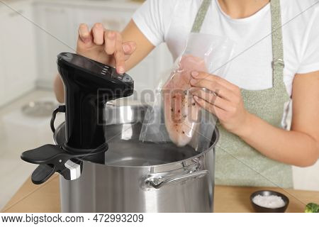 Woman Putting Vacuum Packed Meat Into Pot And Using Thermal Immersion Circulator, Closeup. Sous Vide
