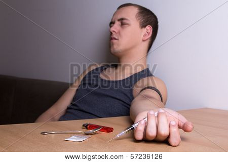 Young Addict With Syringe And Drugs