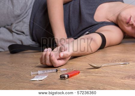 Syringe With Drugs And Addict Lying On The Floor