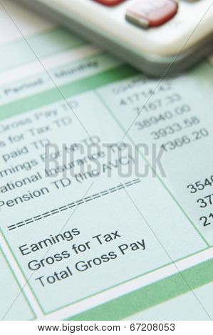 Close Up Of Pay Slip With Calculator