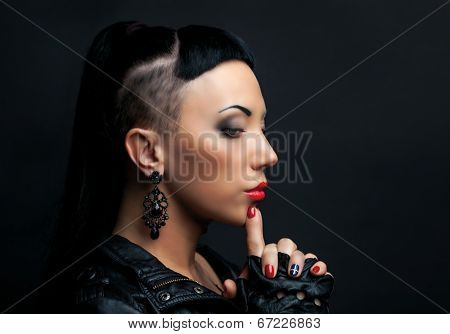 woman with modern unusual haircut with shaved sides, against dark studio background