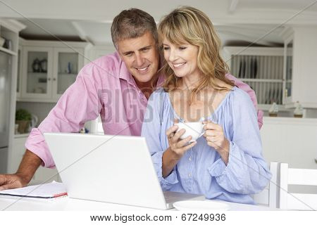 Mid age couple working at home on laptop