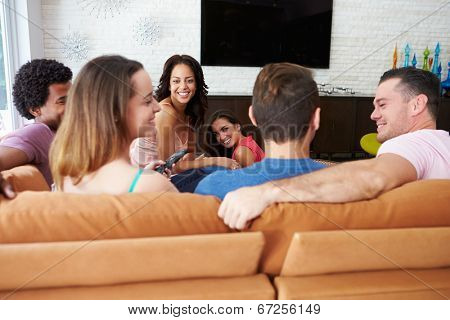 Group Of Friends Sitting On Sofa Watching TV Together