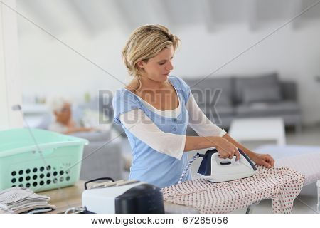 Housekeeper at home ironing clothes for old woman
