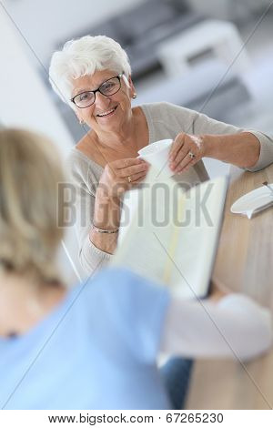 Homecarer reading book to elderly woman 