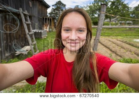 Teengirl taking a self-portrait out in the country house.