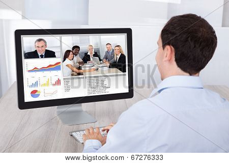 Businessman Video Conferencing With Colleagues On Pc At Desk