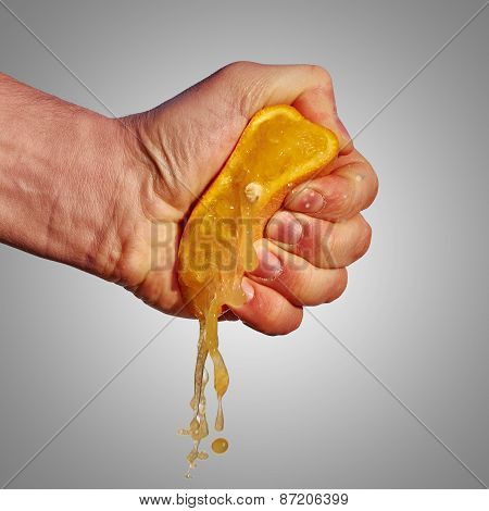Man's Hand Squeezes The Juice From The Orange